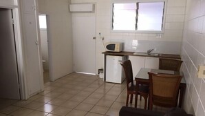 A compact kitchen with a microwave, sink, and small refrigerator. There is a dining area with a table and chairs. - A1 Inn the City (Cairns)