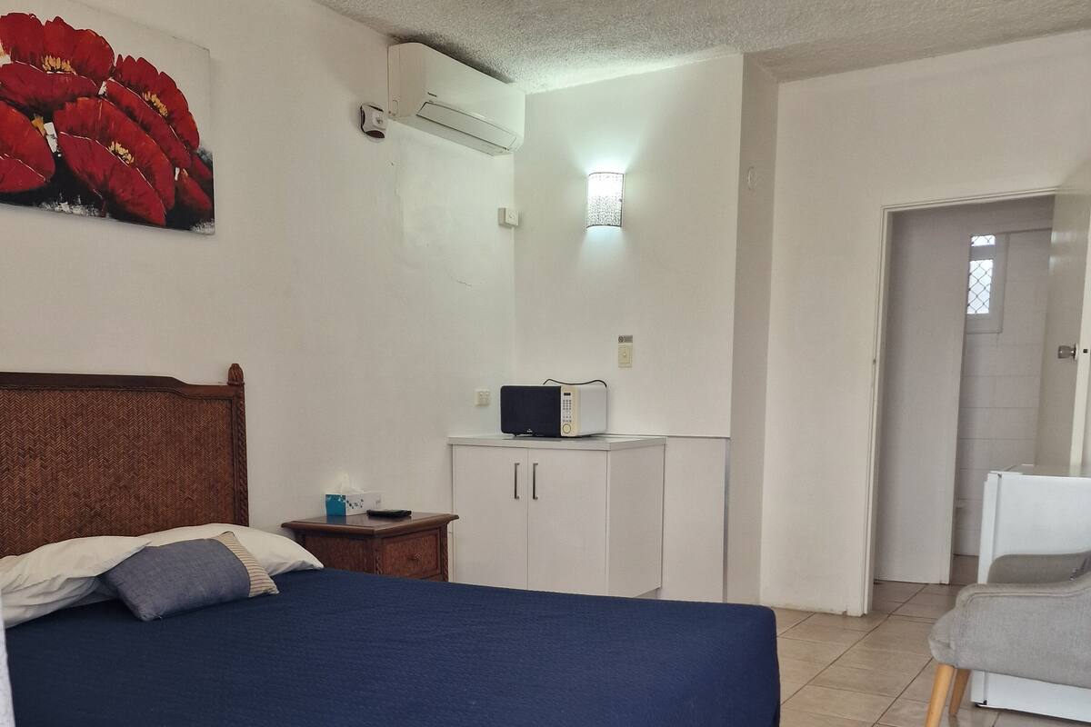 Une chambre à coucher avec un lit, une table de chevet, un four à micro-ondes et une chaise.