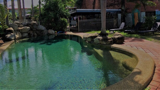 A clear pool surrounded by rocks and a brick pathway. - A1 Inn the City (Cairns)