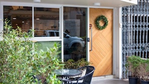 A building entrance with a glass door, a wooden door, a metal gate, and a wreath on the door. - Sarnn Sukhumvit 28 (Bangkok)