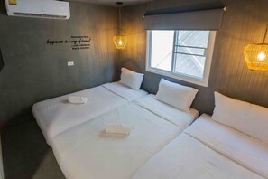 A hotel room with a large bed, a window with blinds, a wall-mounted air conditioner, and a quote about happiness. - Sarnn Sukhumvit 28 (Bangkok)