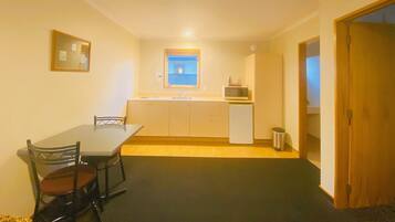 A compact kitchen with a dining table and chairs, a microwave, and a small window.