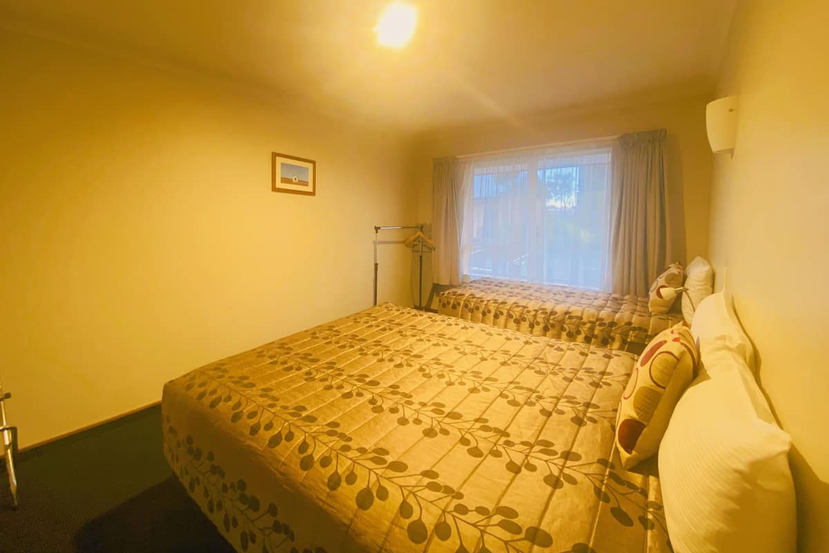 A hotel room with a bed, a window with curtains, a bedside table, and a picture on the wall.