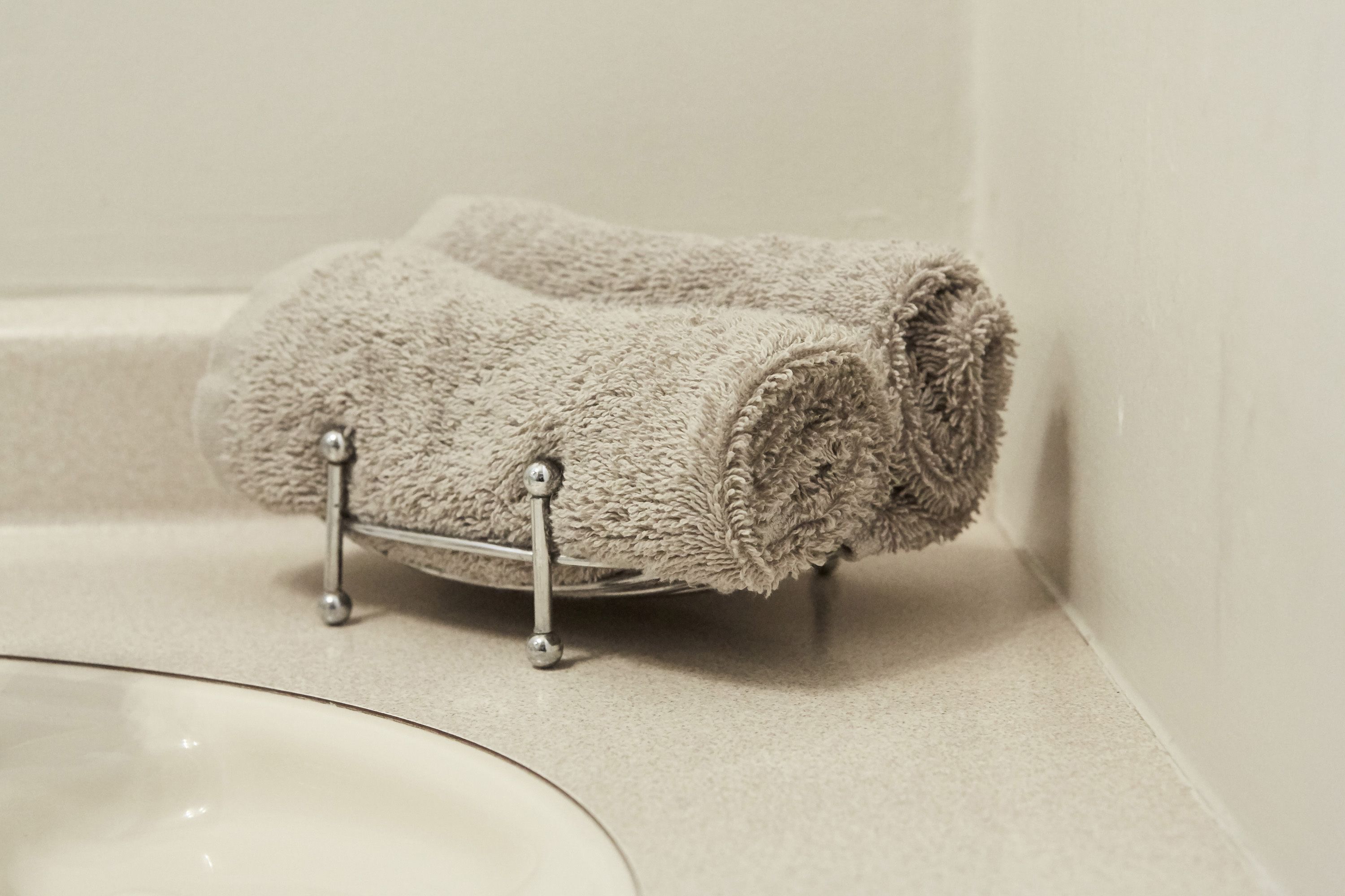 Une salle de bain avec une serviette enroulée sur un porte-serviettes en métal.