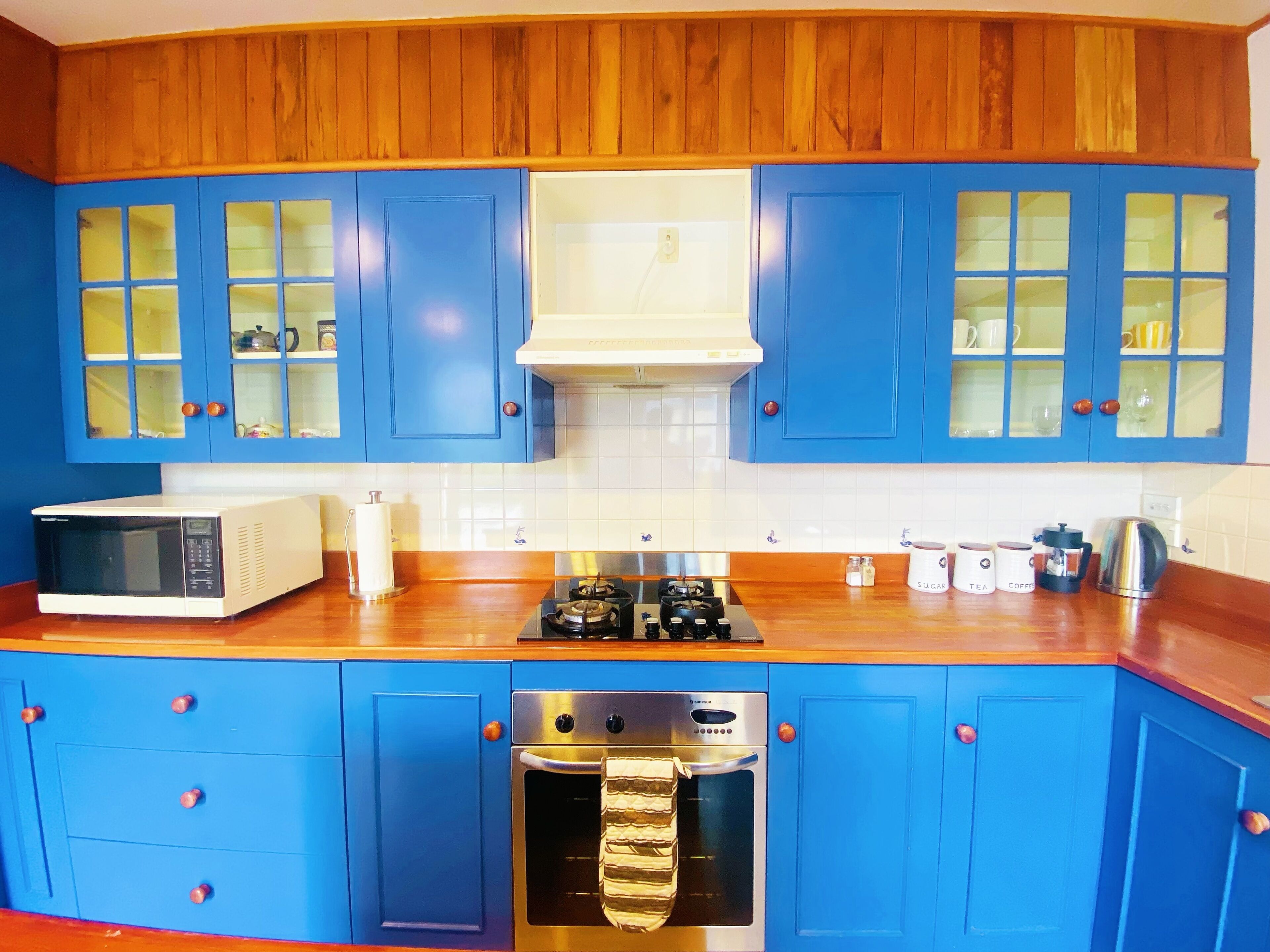 A kitchen with blue cabinets, a microwave, a stove, and an oven.