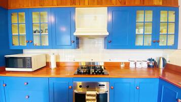 A kitchen with blue cabinets, a microwave, a stove, and an oven.