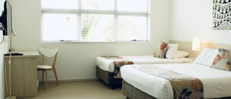 A hotel room with two beds, a desk, and a chair.