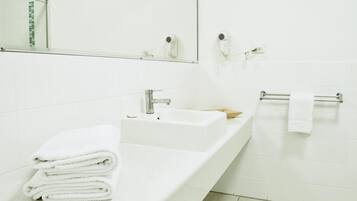 Un baño moderno con un lavamanos blanco, un espejo y un perchero para toallas.