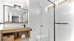 Ein modernes Badezimmer mit Duschkabine aus Glas, einem Holzwaschtisch und einem großen Spiegel.