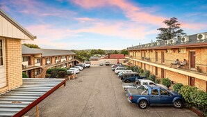 Ein Motel mit mehreren zweistöckigen Gebäuden, einem Parkplatz mit einigen Autos und einem klaren Himmel.