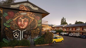 Ein Gebäude mit Wandgemälde, ein Parkplatz und eine Reihe von Motelgebäuden im Hintergrund.