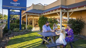 Ein Comfort Inn mit einer Terrasse, auf der eine Familie speist.