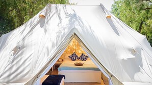 Una carpa con una cama, almohadas y una mesita.