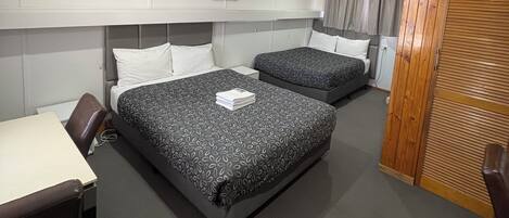 Habitación de hotel con dos camas, un escritorio y un armario.