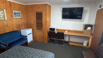 A compact room with two beds, a desk, a television, and a kitchenette.