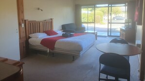 A hotel room with a bed, a desk, a chair, and a television.