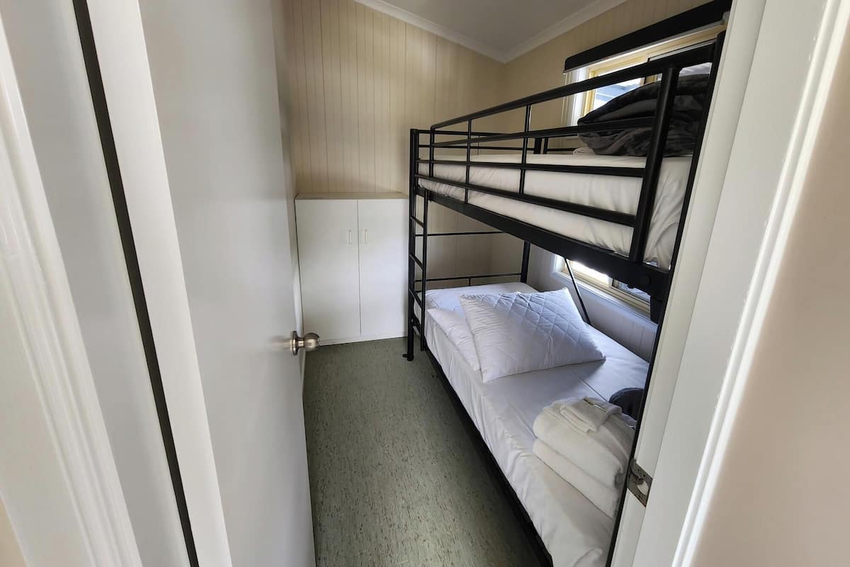 Una habitación pequeña con literas, un armario y una puerta.