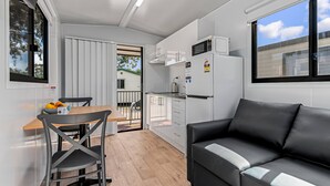 Un espacio habitable compacto con kitchenette, un comedor con mesa y sillas, y un sofá.