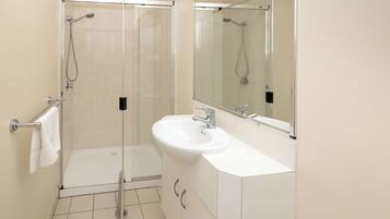 Un bagno moderno con doccia vetro, lavandino bianco e uno specchio grande.