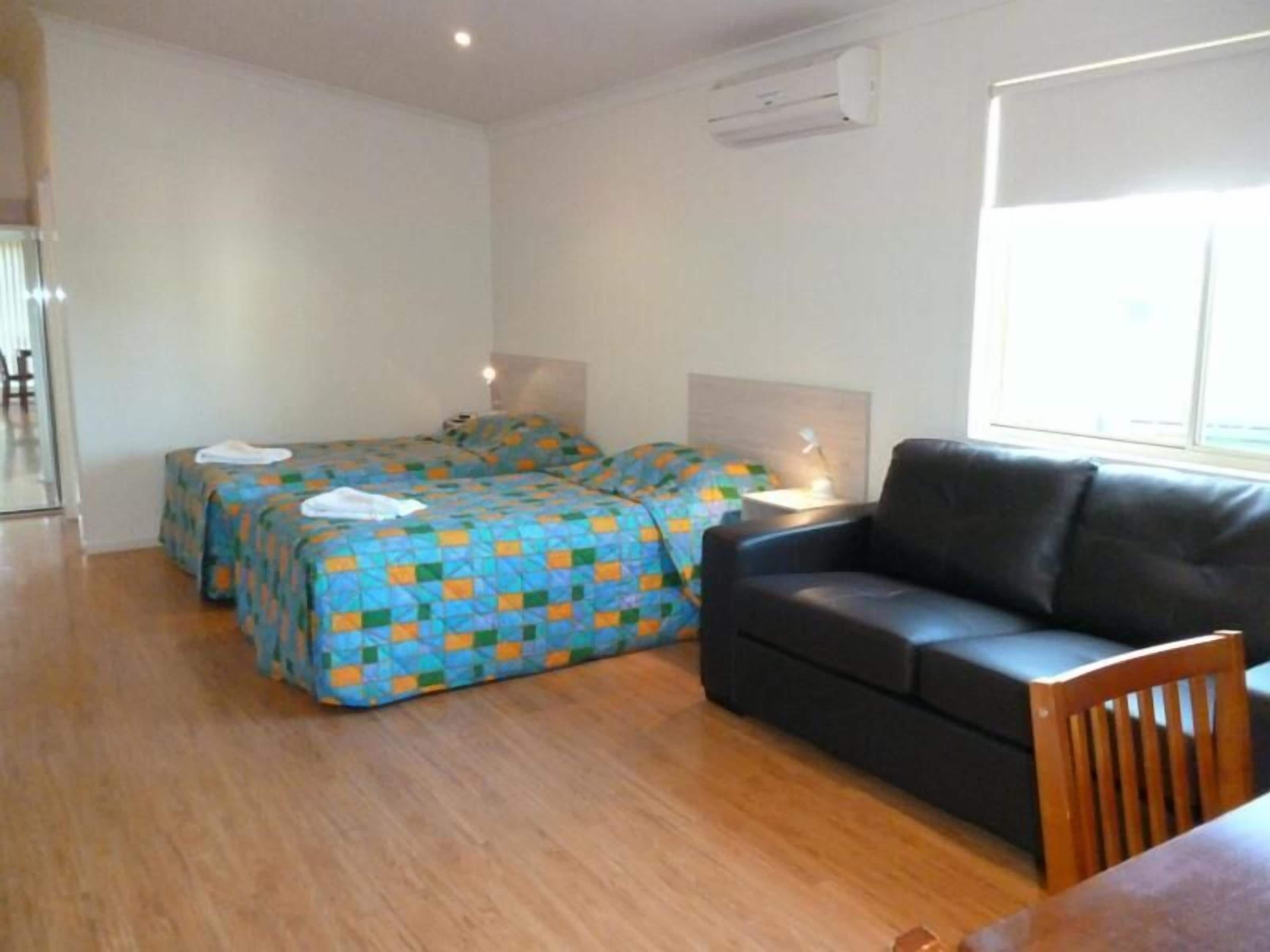 A room with two beds, a sofa, a table, and a window.