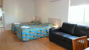 A room with two beds, a sofa, a table, and a window.