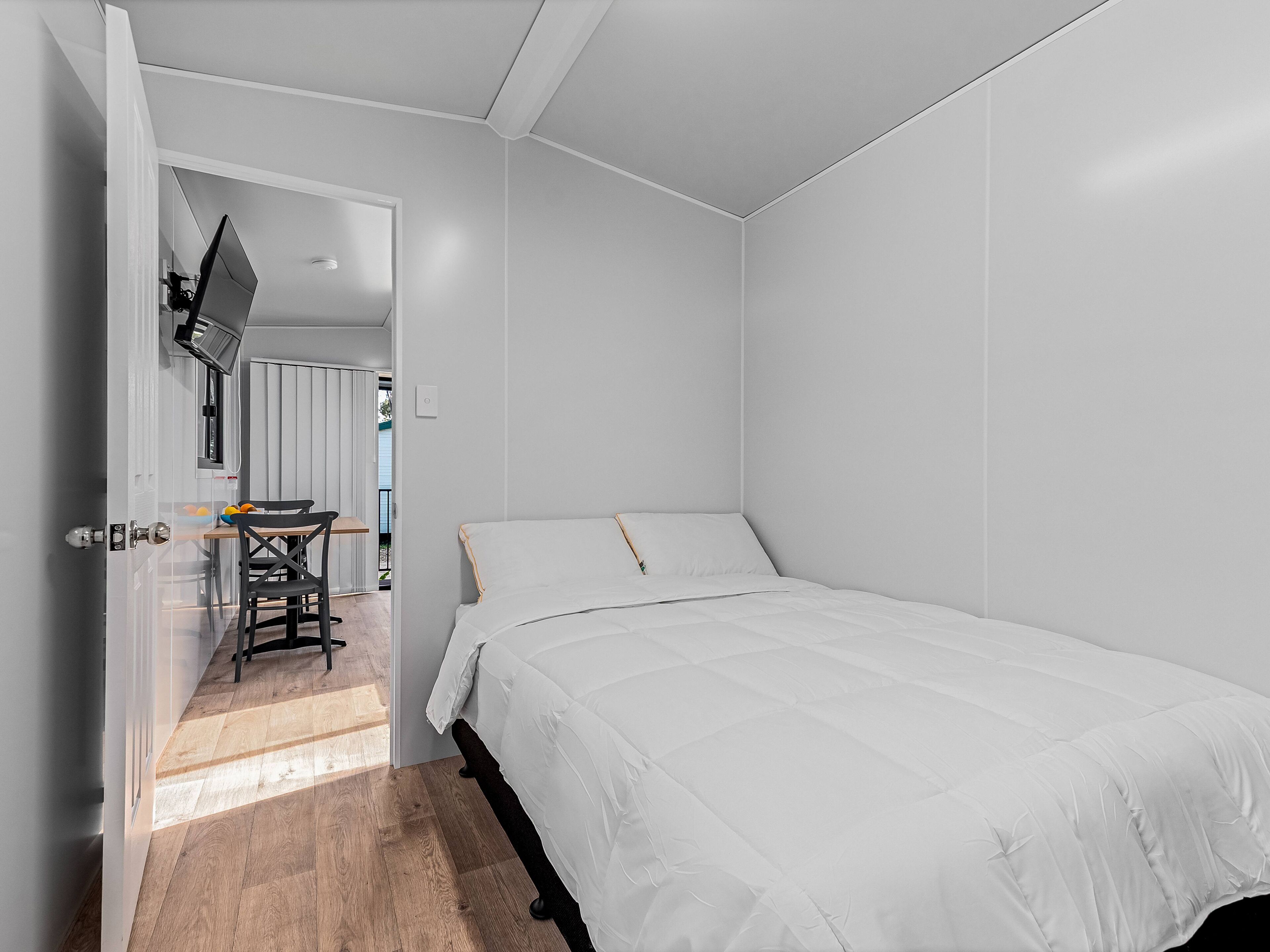 Un dormitorio con una cama, un escritorio con una silla y una ventana.