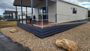 Una casa móvil moderna con un porche cubierto y un camino de entrada de grava.