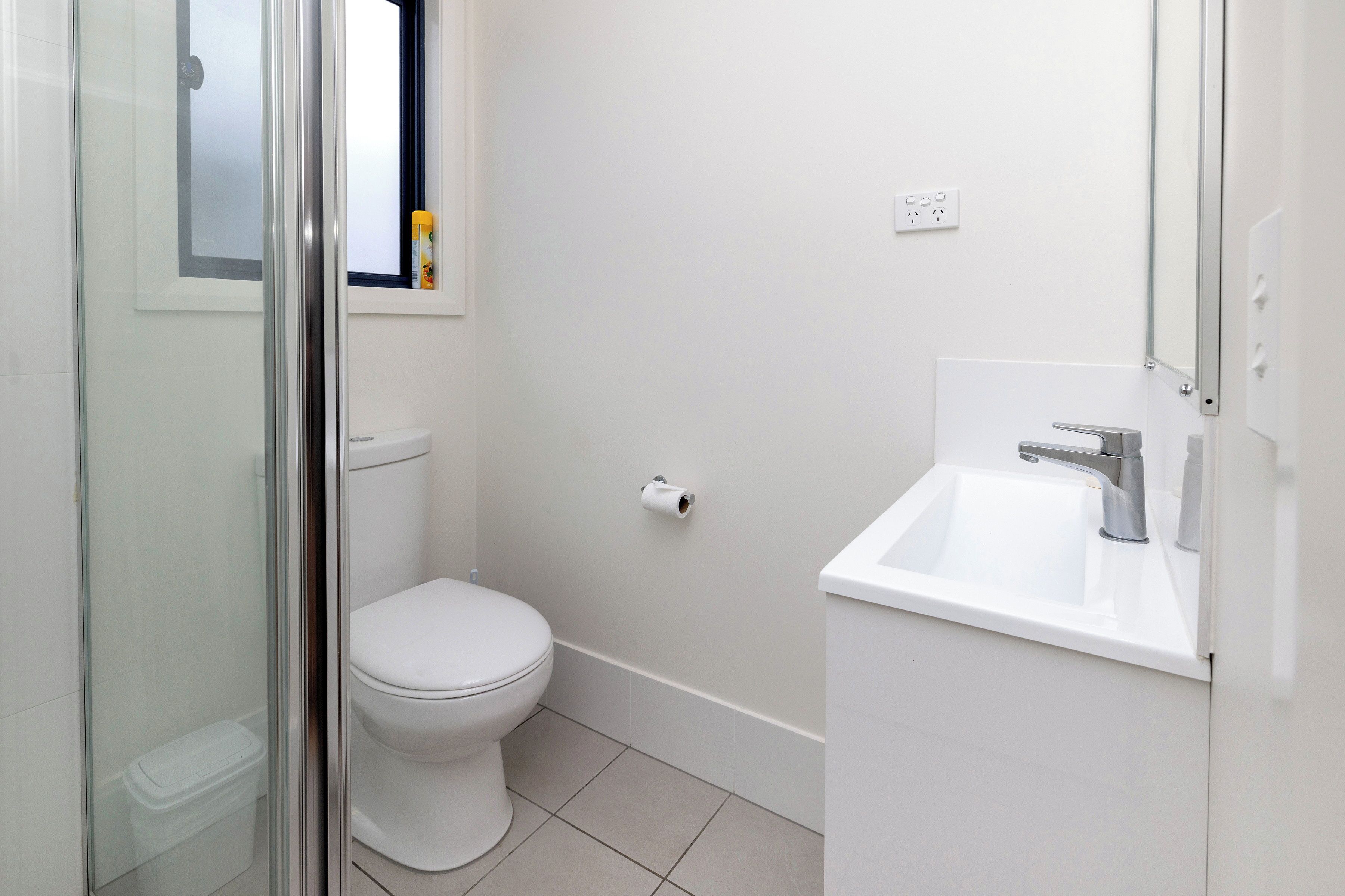 Een badkamer met toilet, wastafel en douchecabine.