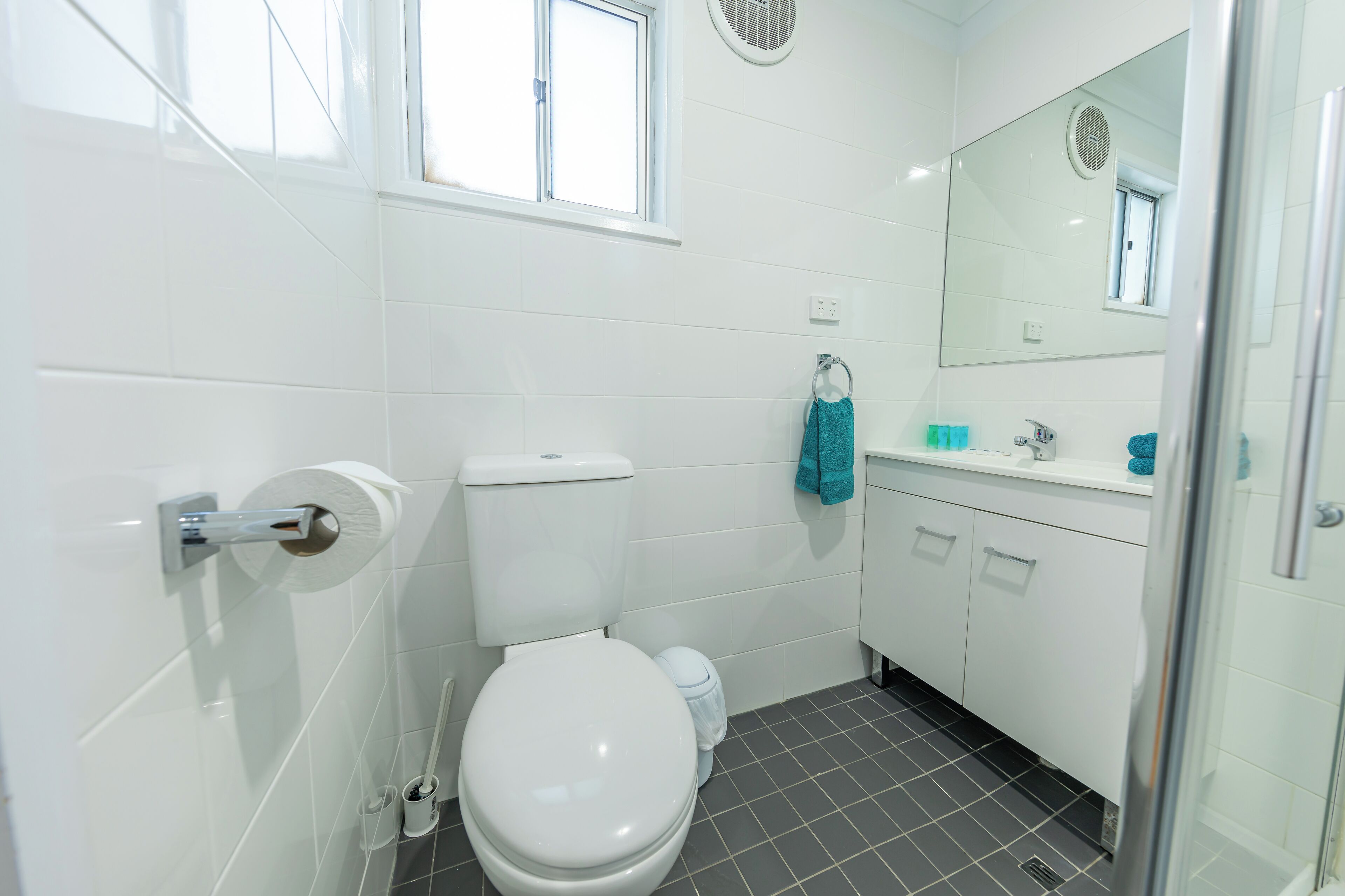 A modern bathroom with a toilet, sink, and mirror.