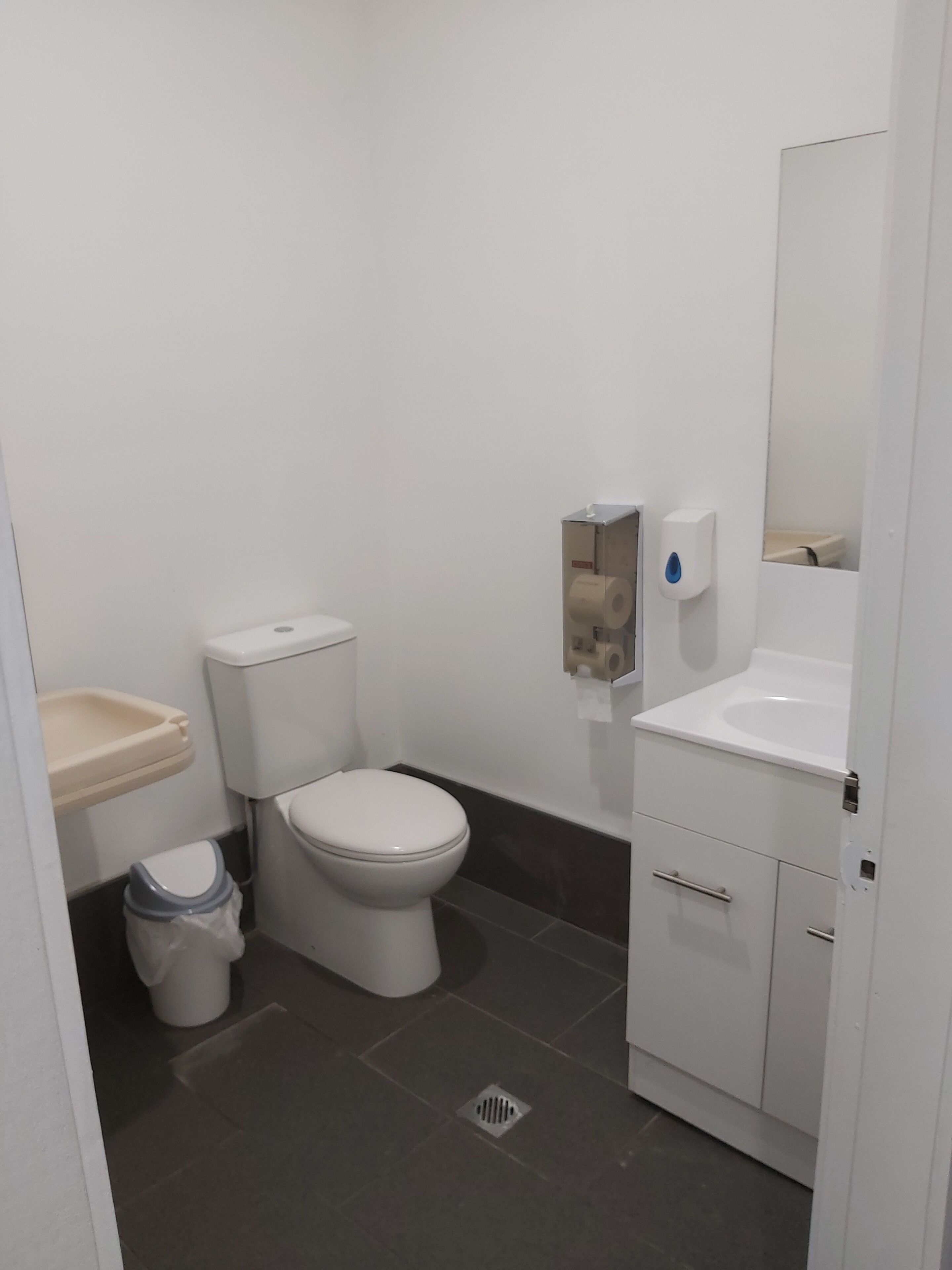 Une petite salle de bain propre, équipée de toilettes, d’un lavabo et d’un miroir.