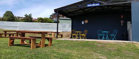A covered outdoor area with a picnic table and colorful chairs, labeled as a Family BBQ Area.