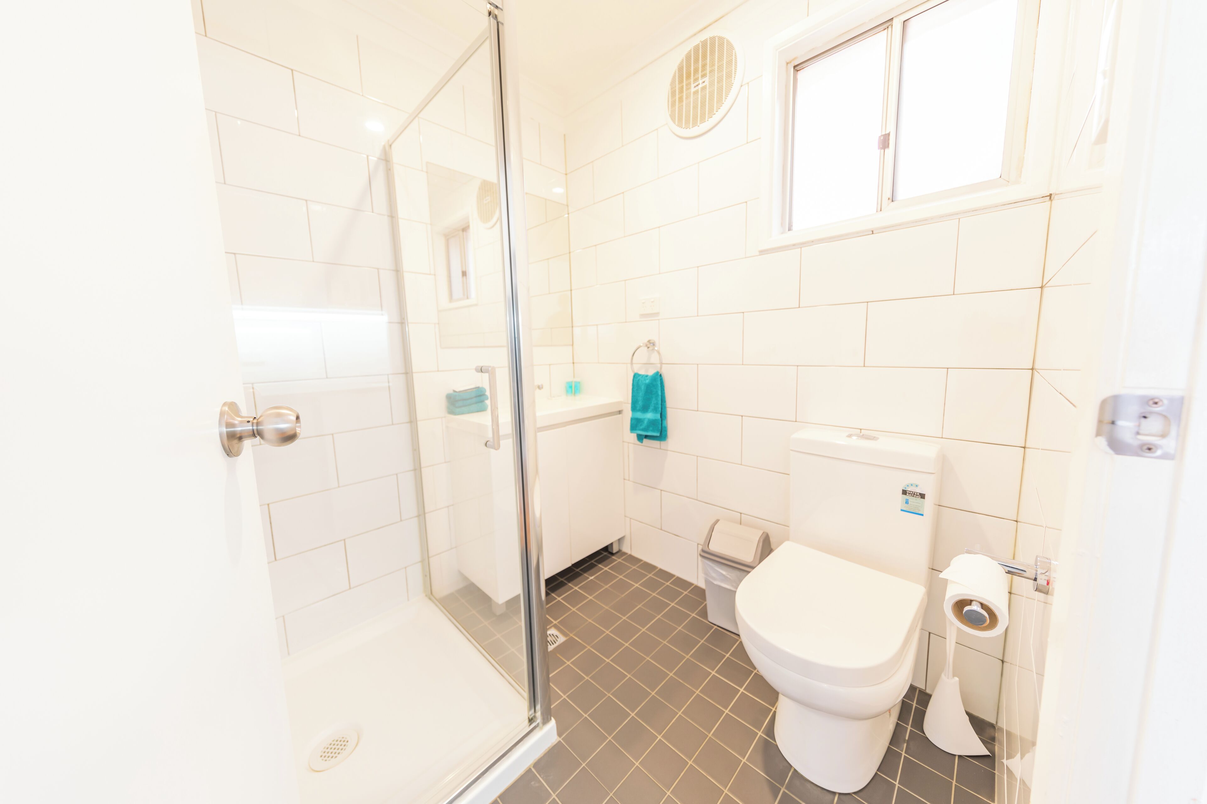 A bathroom with a glass shower enclosure, a toilet, and a sink.