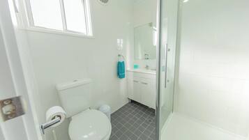 A bathroom with a toilet, sink, and shower.