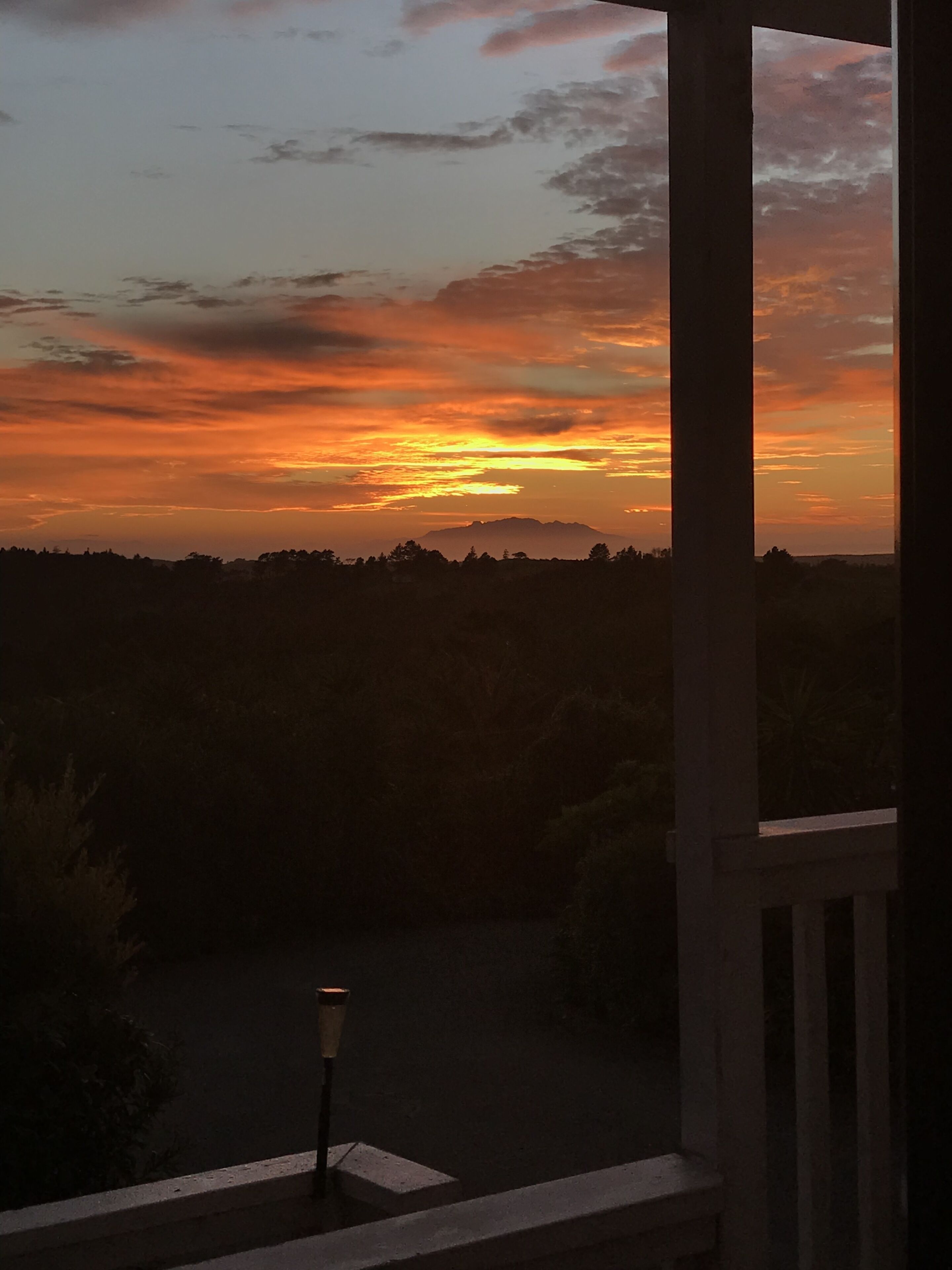 Une vue sur le coucher de soleil depuis un balcon doté d’une balustrade et éclairé par un lampadaire.