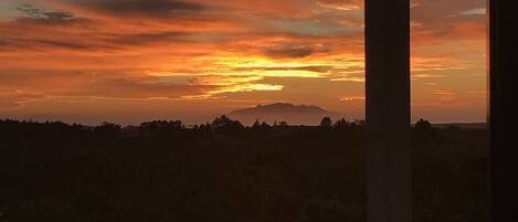 Une vue sur le coucher de soleil depuis un balcon doté d’une balustrade et éclairé par un lampadaire.