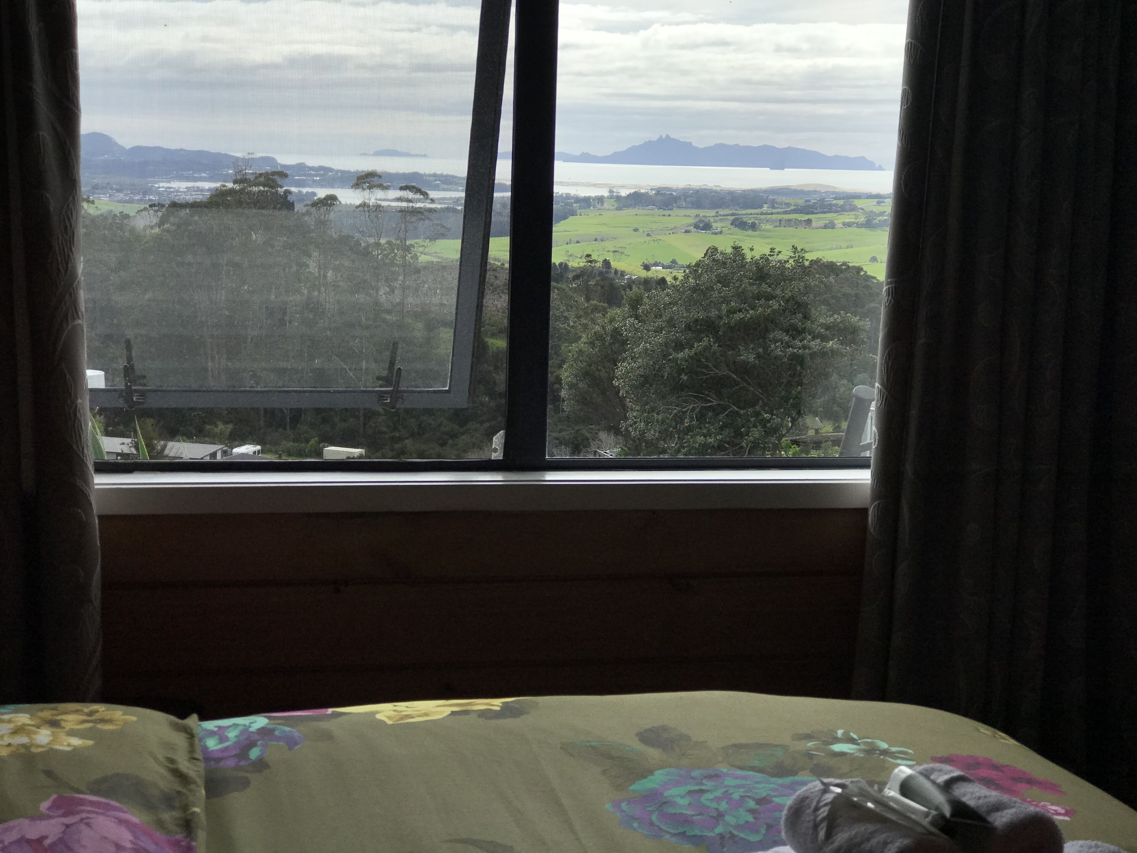 A bedroom with a window overlooking a landscape.