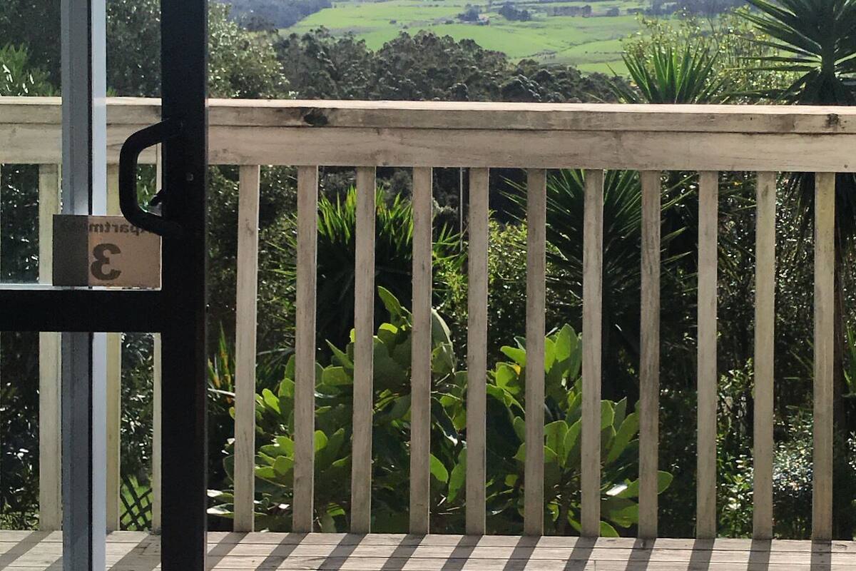 Un balcon offrant une vue sur un paysage verdoyant et des montagnes lointaines.