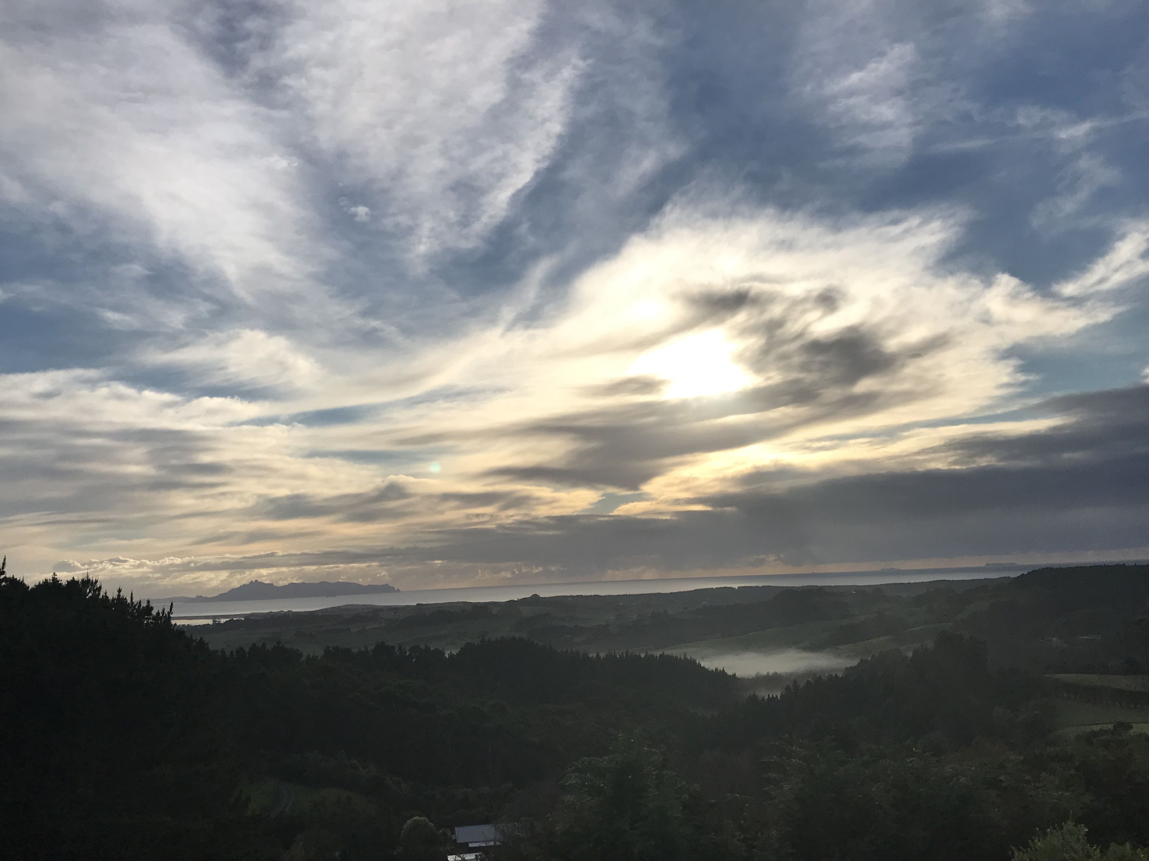 Un paisaje con un lago, colinas y un cielo nublado.