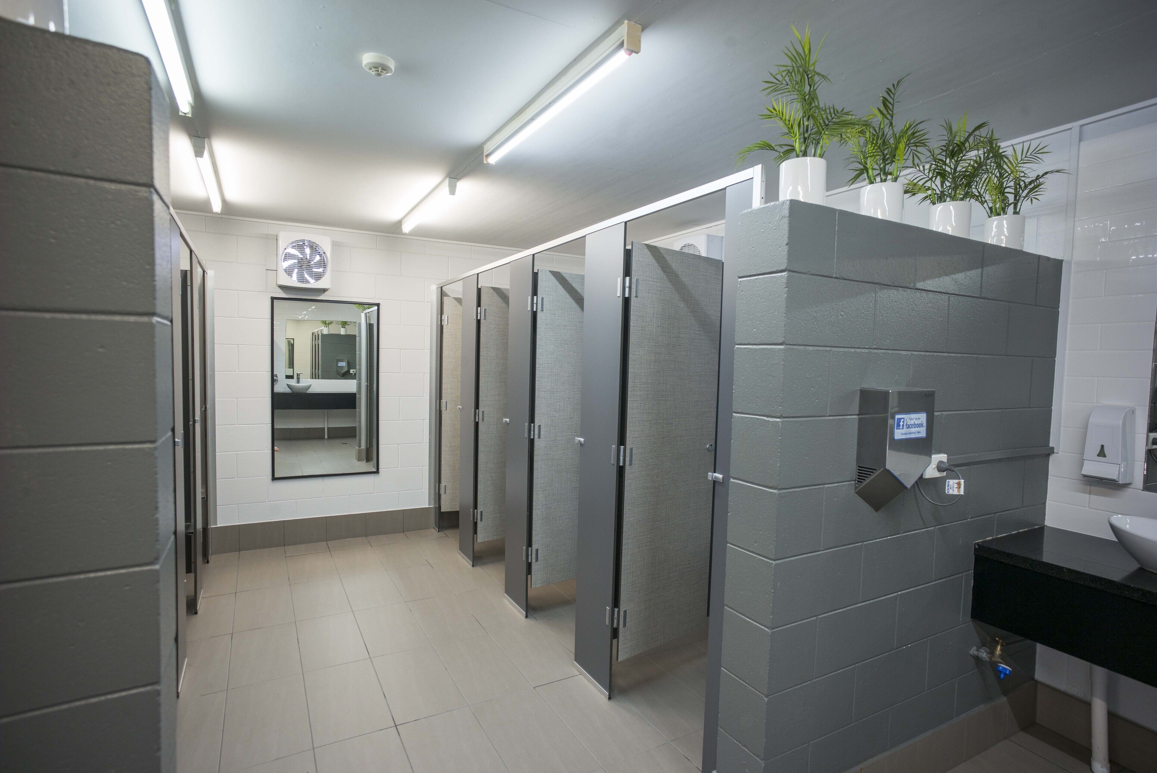 Un baño moderno con cabinas individuales, un secador de manos y un lavabo con encimera negra.