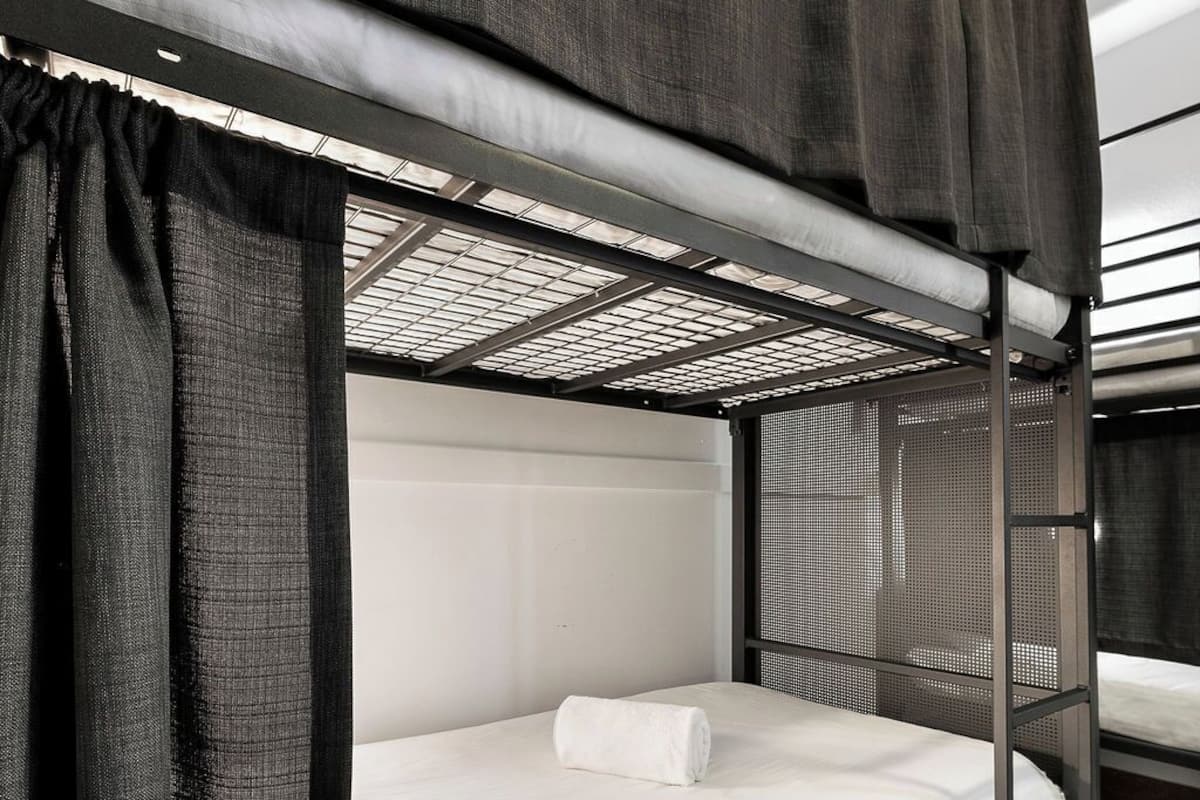 Una cama litera con un colchón blanco y una toalla blanca enrollada.