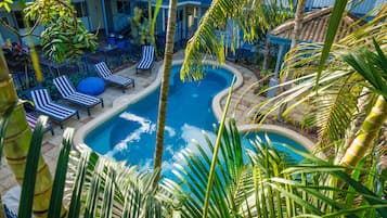 Relax by the serene pool surrounded by lush vegetation and lounge chairs.