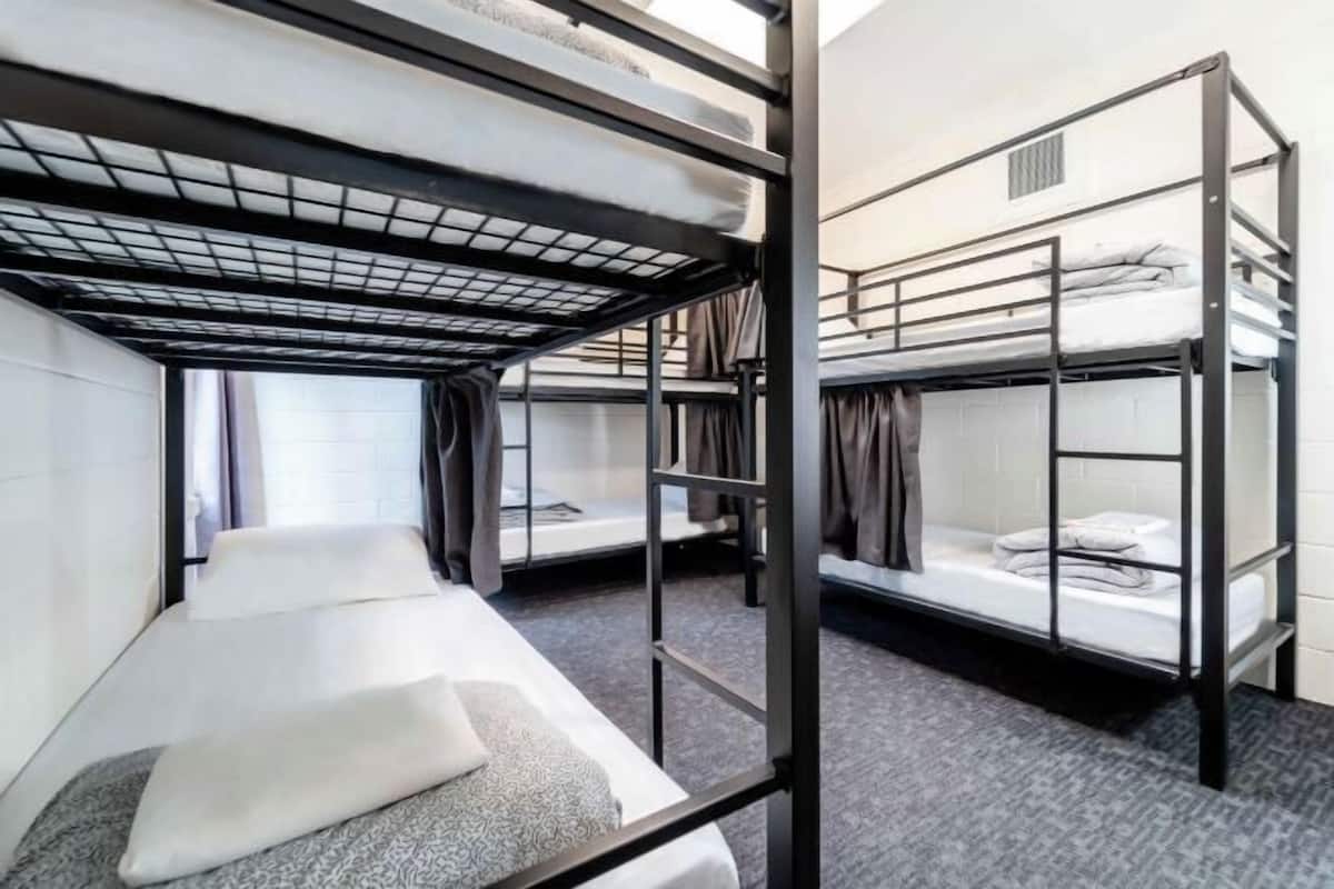Un dormitorio con literas, una ventana con cortinas y una pared blanca.