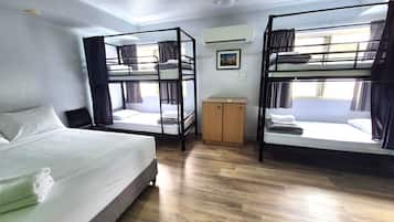 A room with bunk beds, a desk, a wardrobe, and an air conditioning unit.