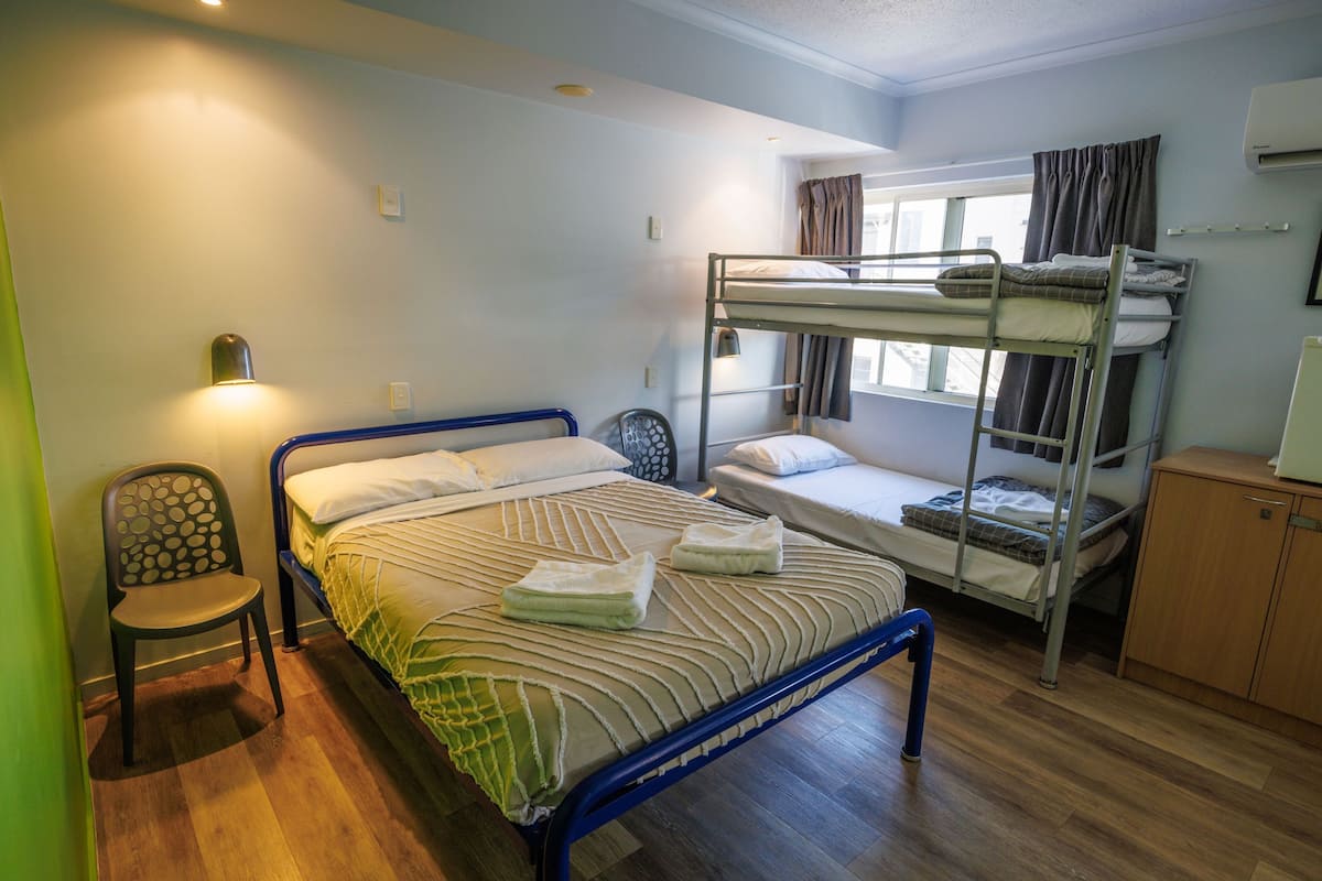 Un dormitorio con literas, una silla, un escritorio y una ventana con cortinas.