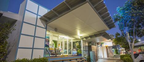 A modern building with a covered entrance, steps leading up to the entrance, and a signboard.