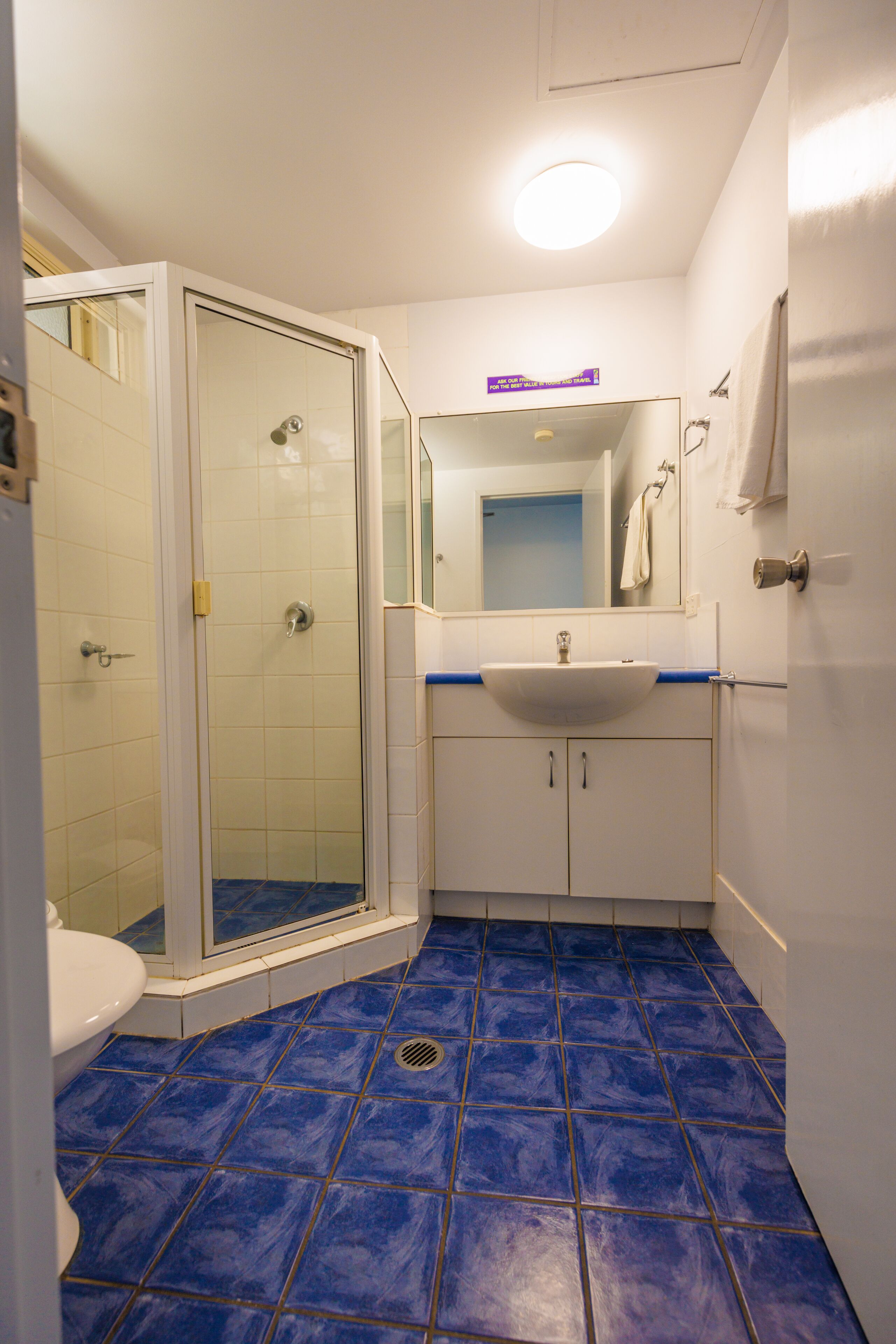 A bathroom with a shower, toilet, sink, and mirror.