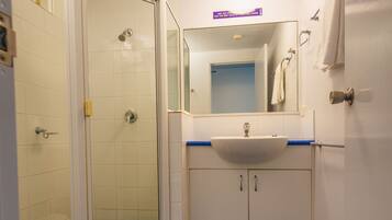 A bathroom with a shower, toilet, sink, and mirror.