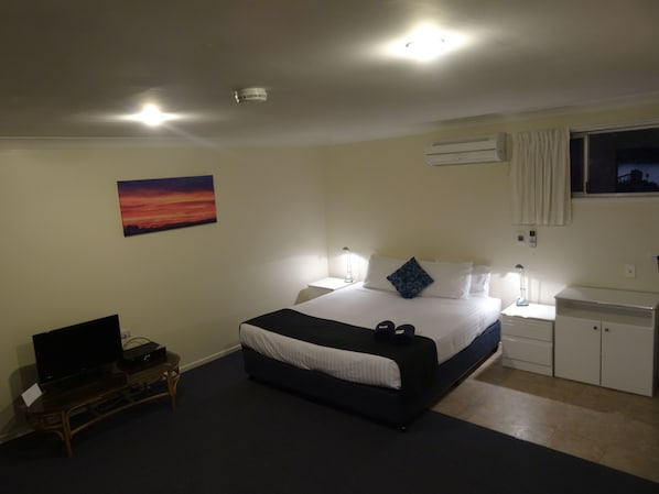 Habitación de hotel con una cama, lámparas de noche, un escritorio, un televisor y un cuadro en la pared.