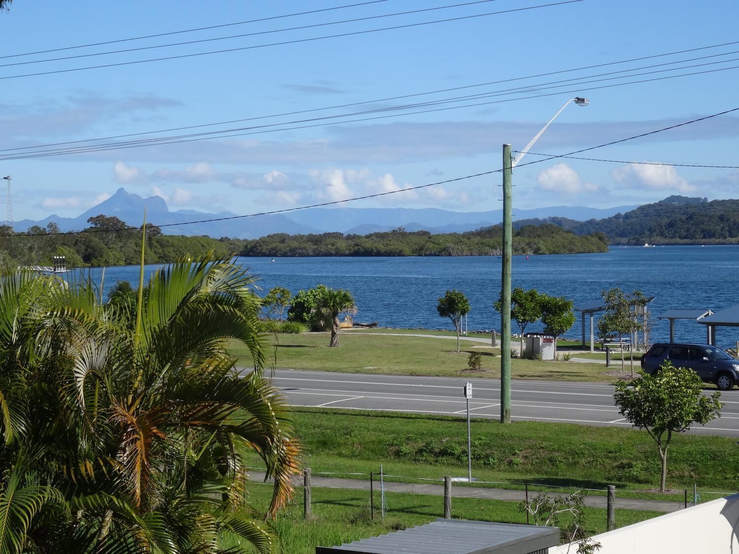 A view of a road with a body of water and mountains in the background.