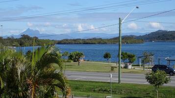 A view of a road with a body of water and mountains in the background.